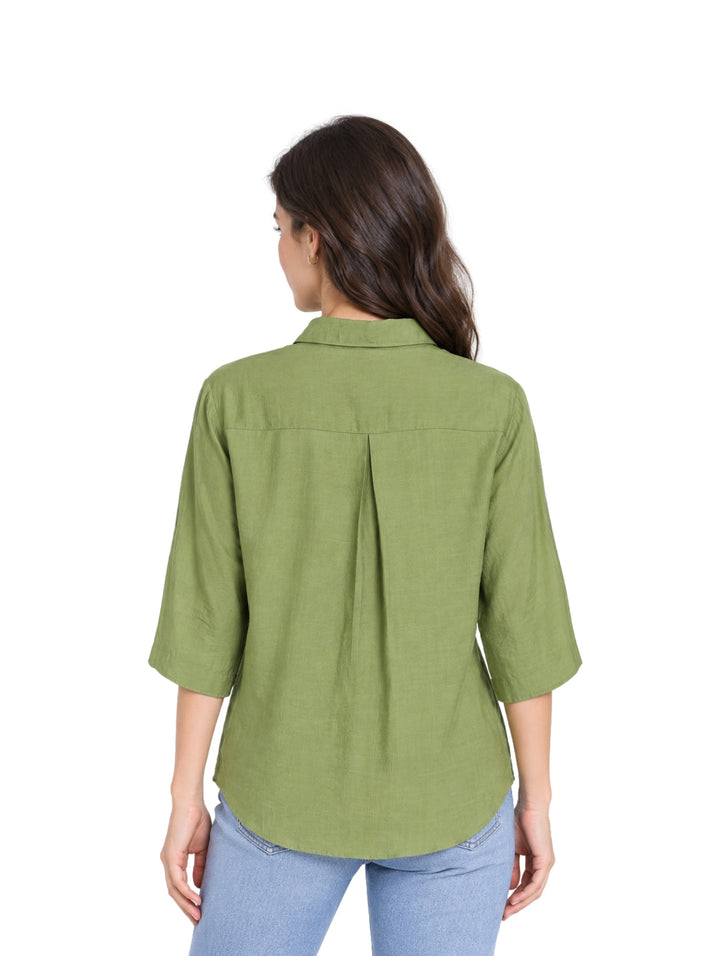 Mujer vistiendo una camisa verde de botones con mangas 3/4 y pantalones azules.