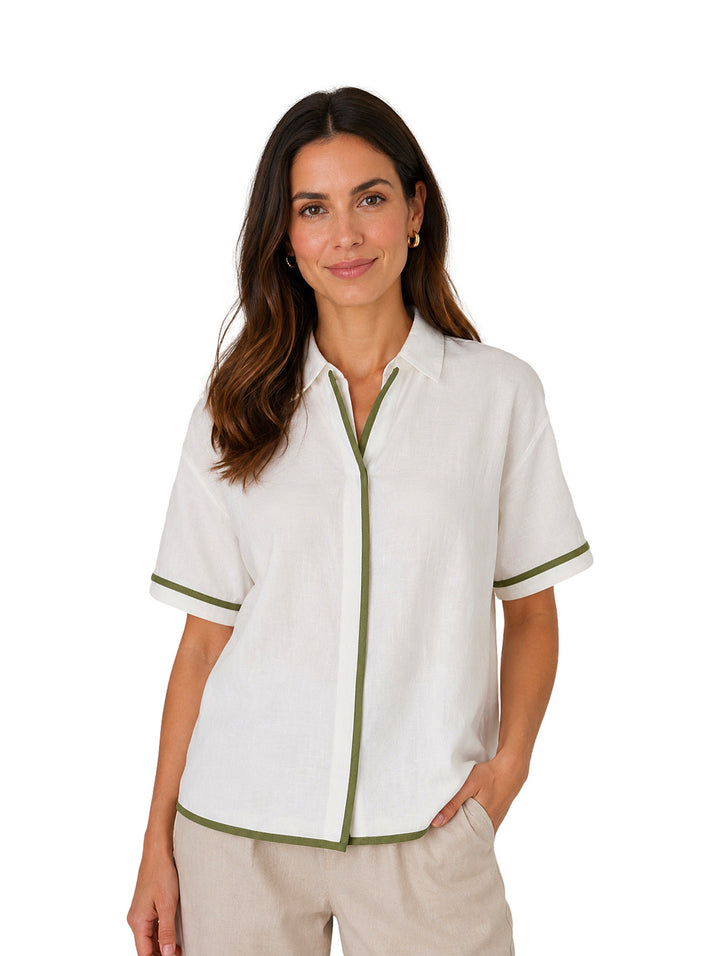 Mujer vistiendo camisa blanca de manga corta con detalles en color verde en los bordes y cuello.