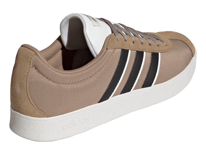 Tenis Adidas color marrón con tres franjas negras laterales y suela blanca.