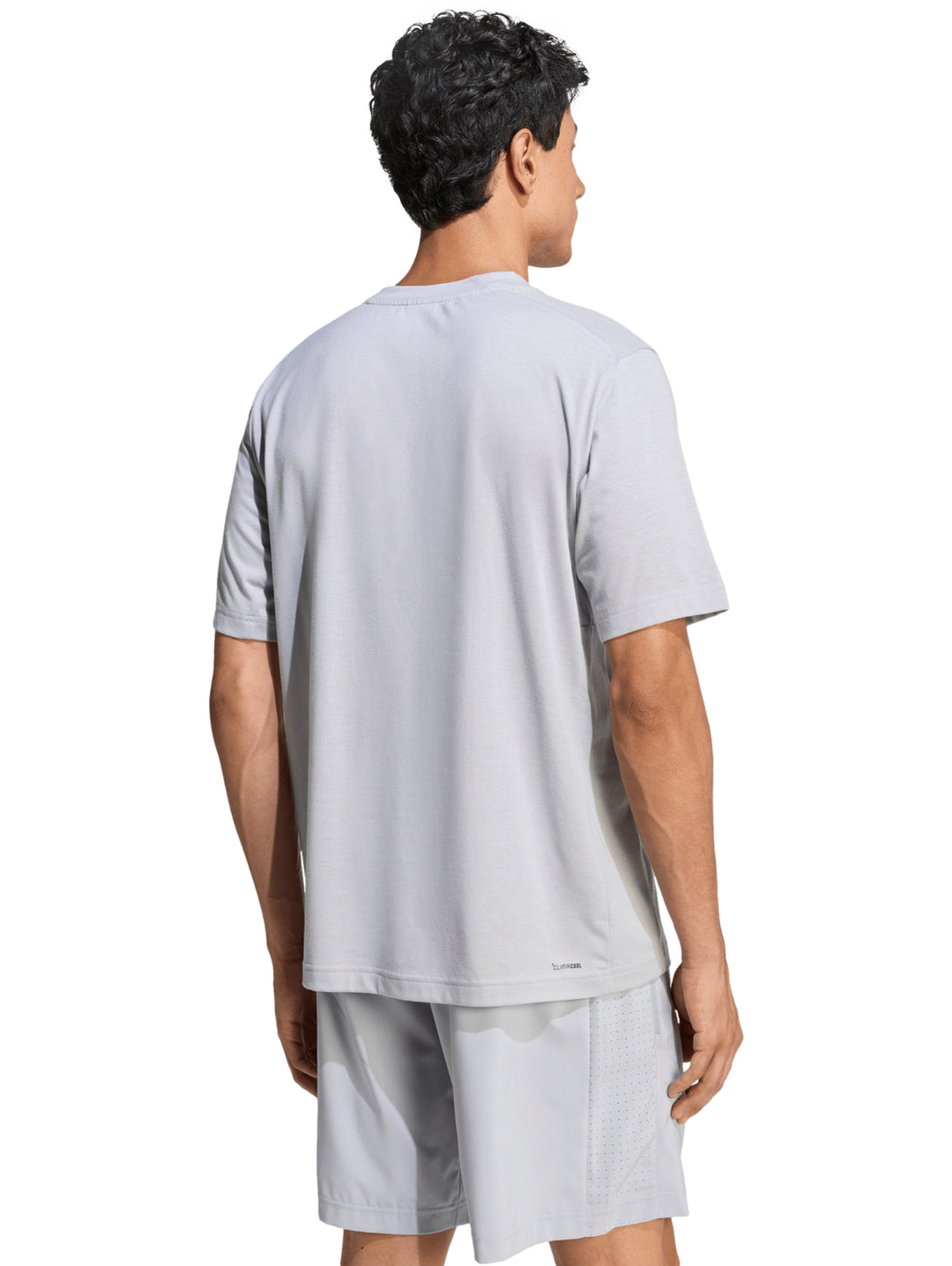 Hombre vistiendo conjunto deportivo Adidas de color gris compuesto por camiseta y shorts.