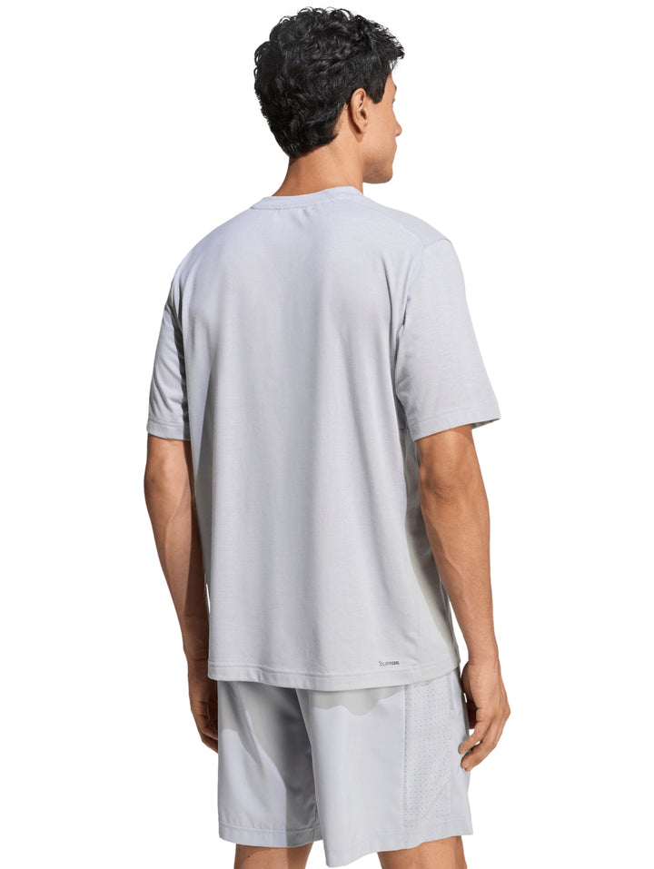 Hombre vistiendo conjunto deportivo Adidas de color gris compuesto por camiseta y shorts.