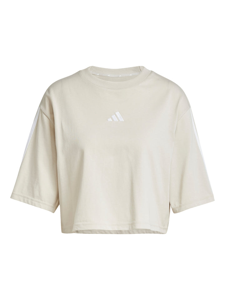 Mujer vistiendo playera crop top y shorts deportivos color beige con rayas blancas de Adidas.