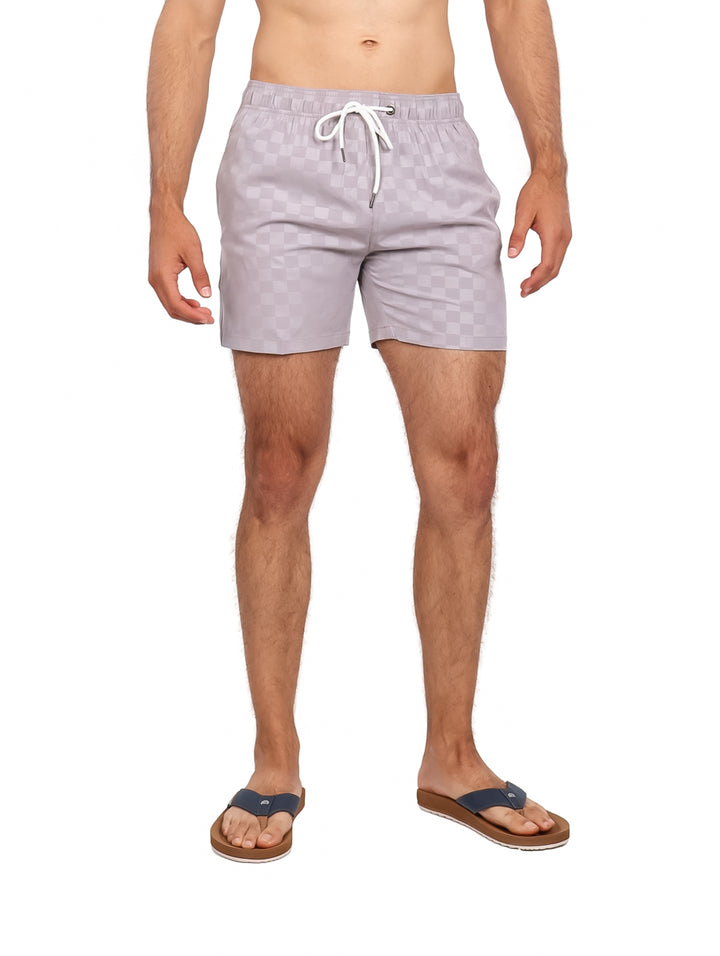 Hombre vistiendo traje de baño corto color gris claro con patrón de cuadros y cordón blanco.
