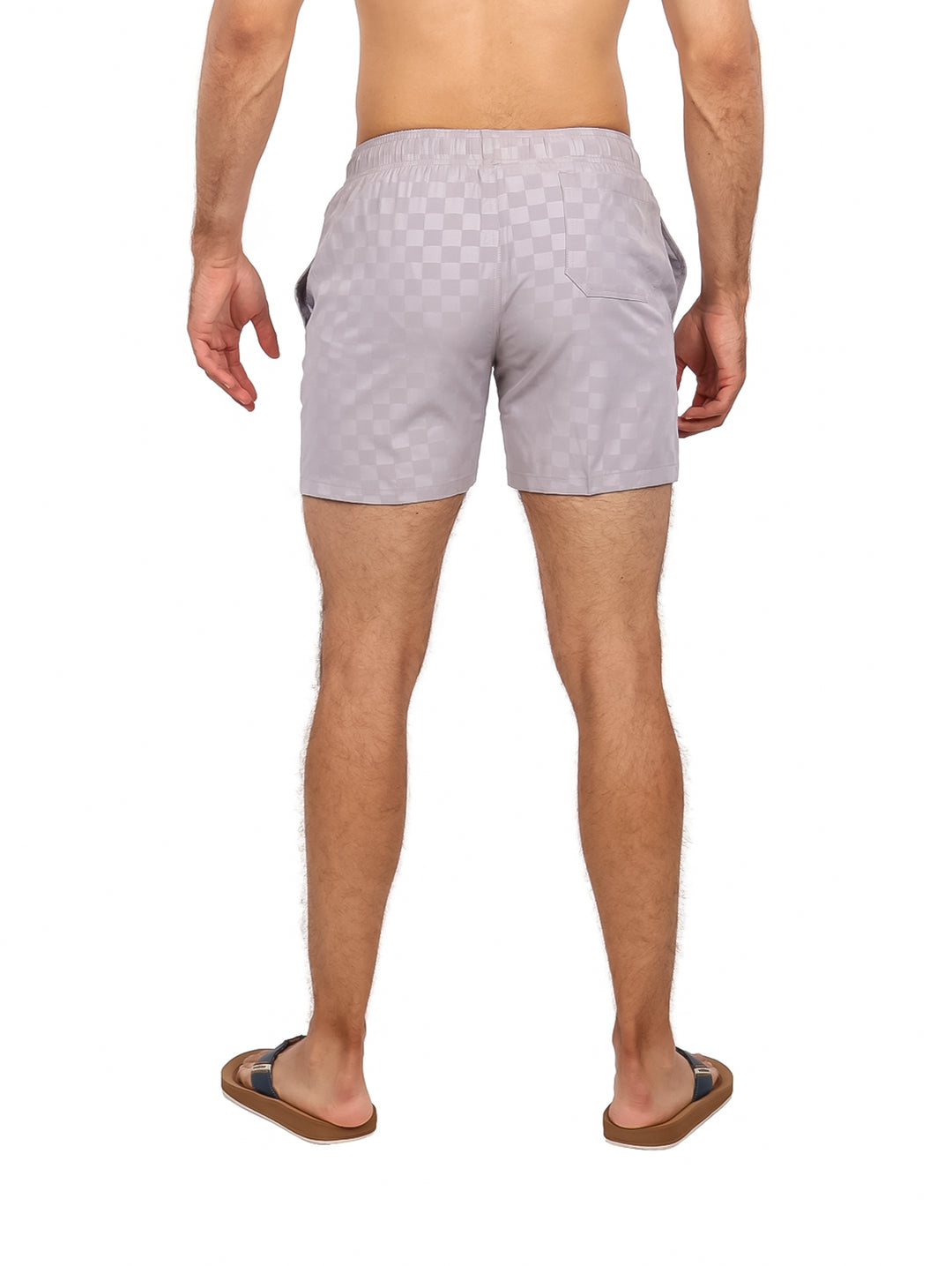 Hombre vistiendo traje de baño corto color gris claro con patrón de cuadros y cordón blanco.