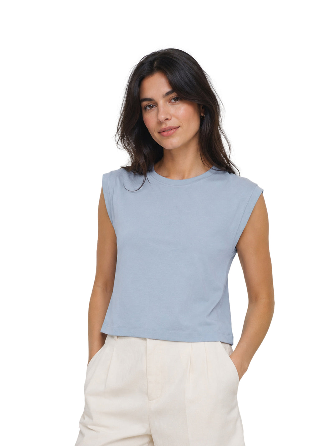 Mujer modelando una blusa azul sin mangas de cuello redondo y pantalones color crema.