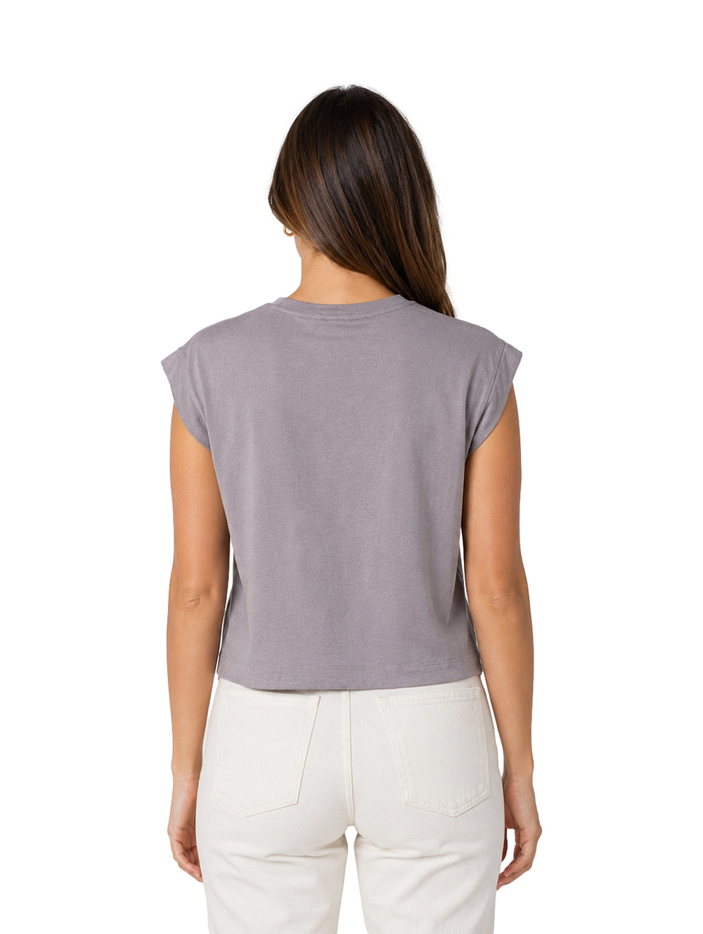 Mujer vistiendo una blusa gris sin mangas de cuello redondo y pantalones blancos.