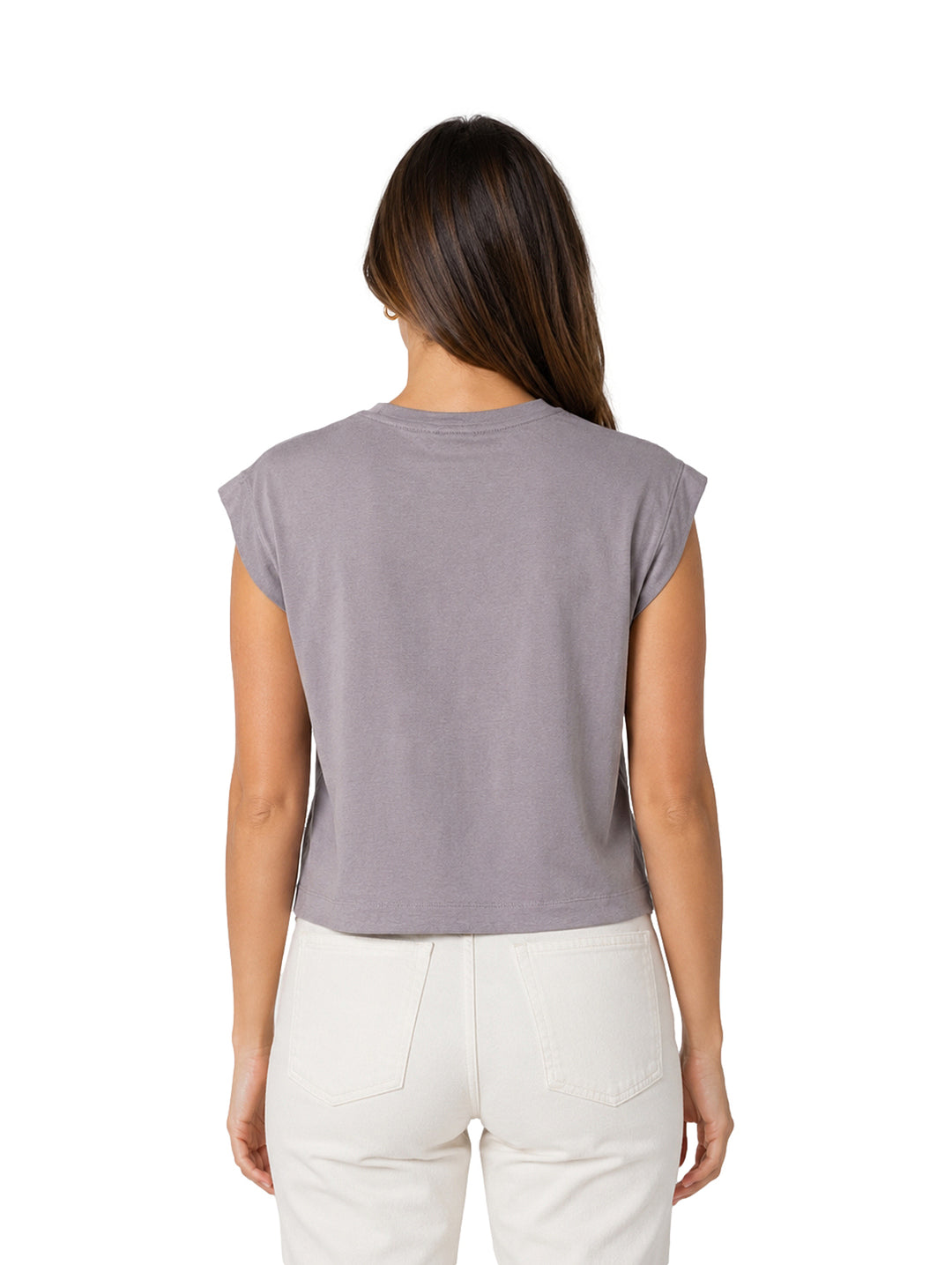 Mujer vistiendo una blusa gris sin mangas de cuello redondo y pantalones blancos.