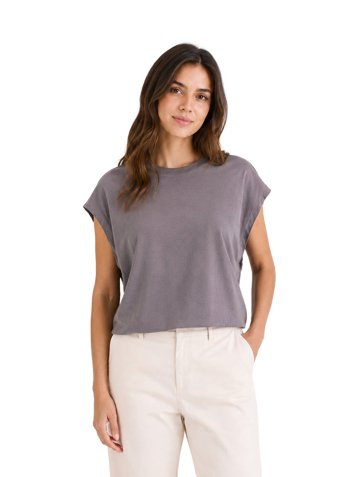 Mujer vistiendo una blusa color gris de manga corta y pantalones color crema.