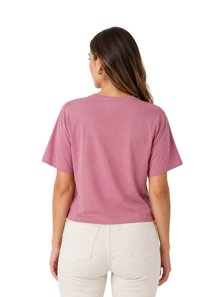 Mujer vistiendo una blusa de color rosa oscuro con cuello redondo y manga corta.