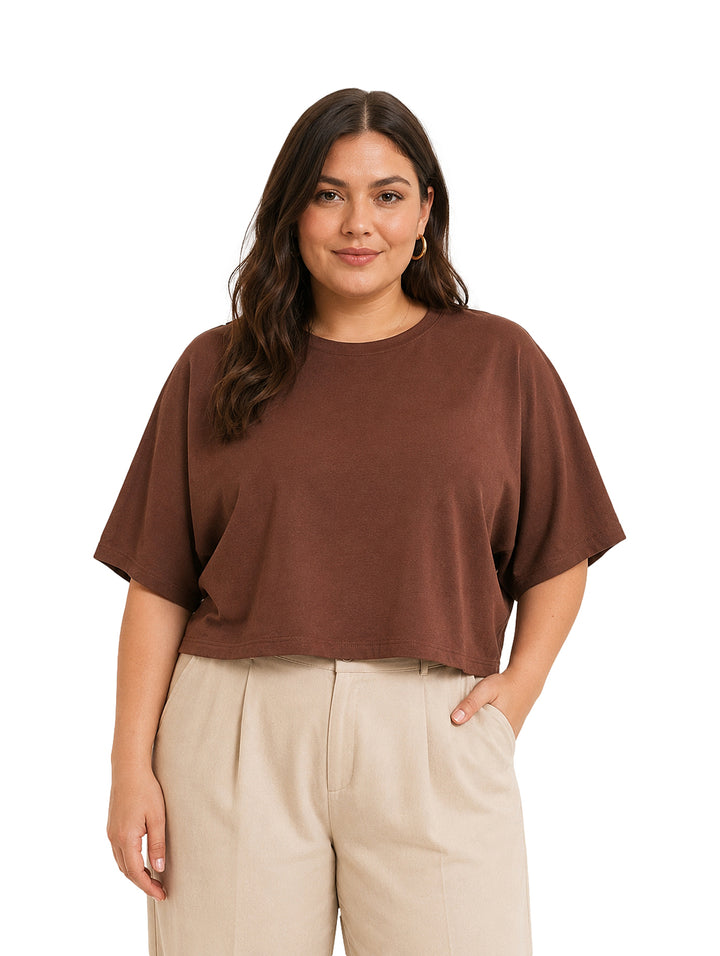 Mujer vistiendo una blusa corta de color marrón con cuello redondo y mangas cortas.