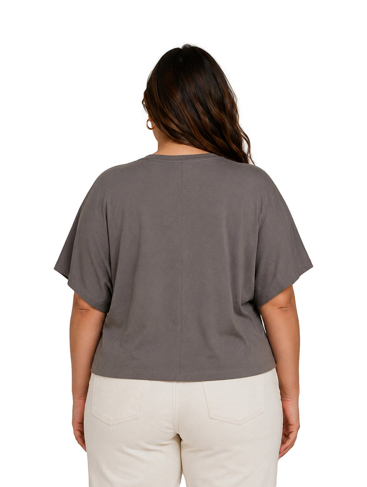 Mujer vistiendo blusa holgada color gris y pantalones blancos.