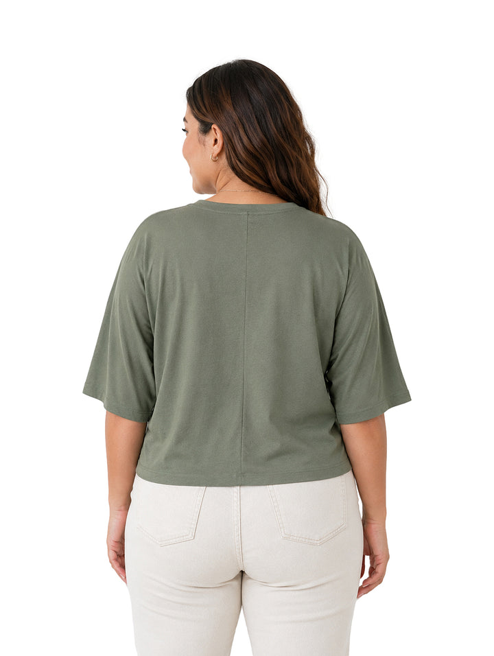 Mujer vistiendo una blusa color verde de corte holgado y cuello redondo.
