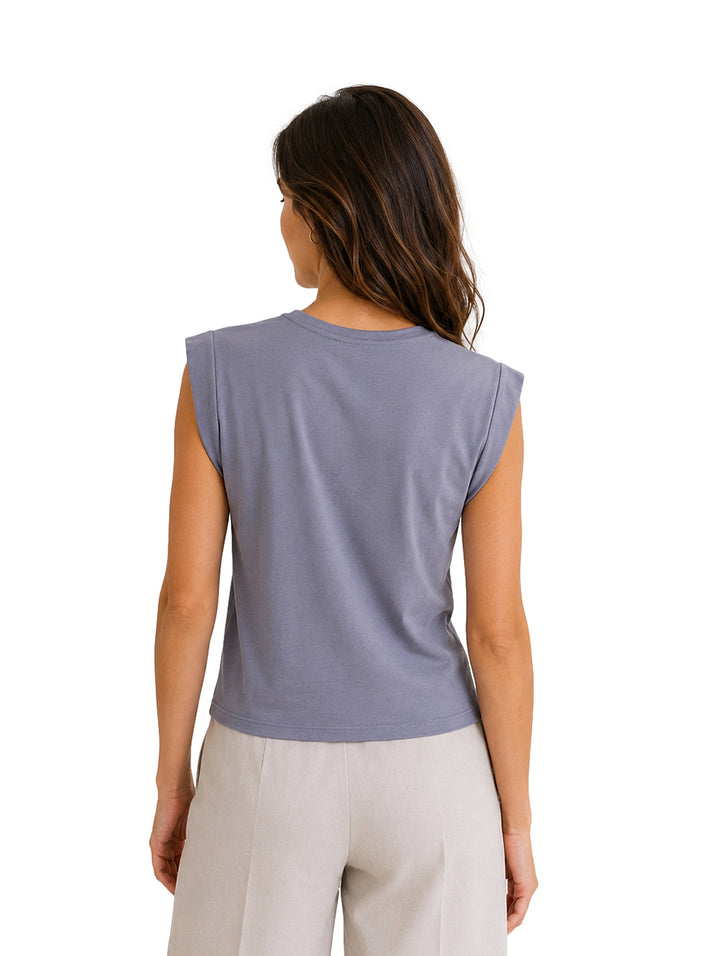 Mujer vistiendo una blusa sin mangas de color gris claro y pantalones claros.