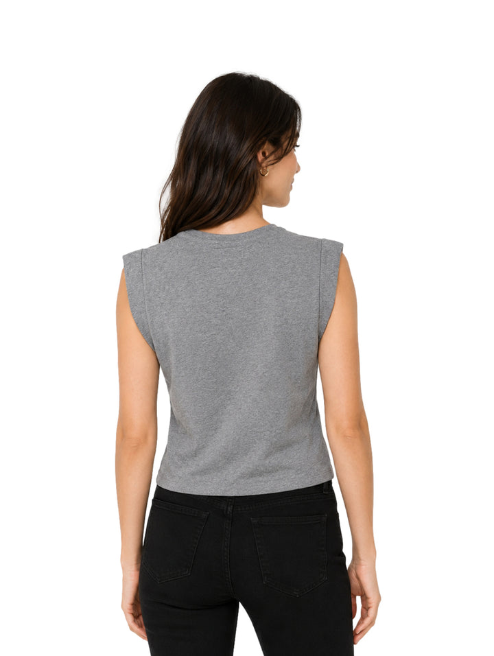 Mujer vistiendo una blusa gris melange sin mangas y pantalones negros sobre fondo blanco.