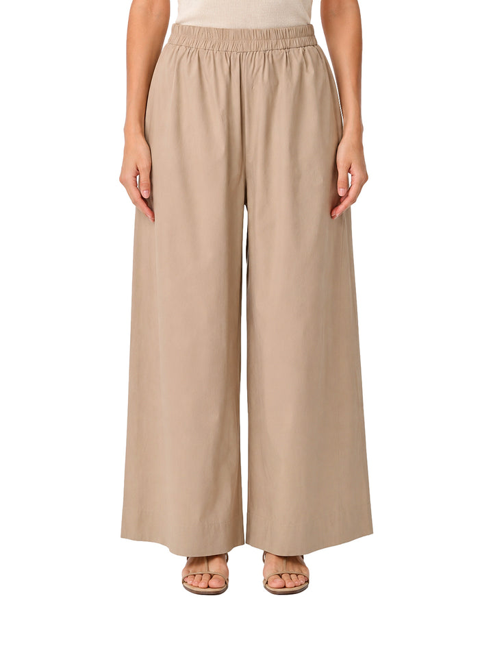 Mujer vistiendo pantalones de pierna ancha en color camel con cintura elástica.