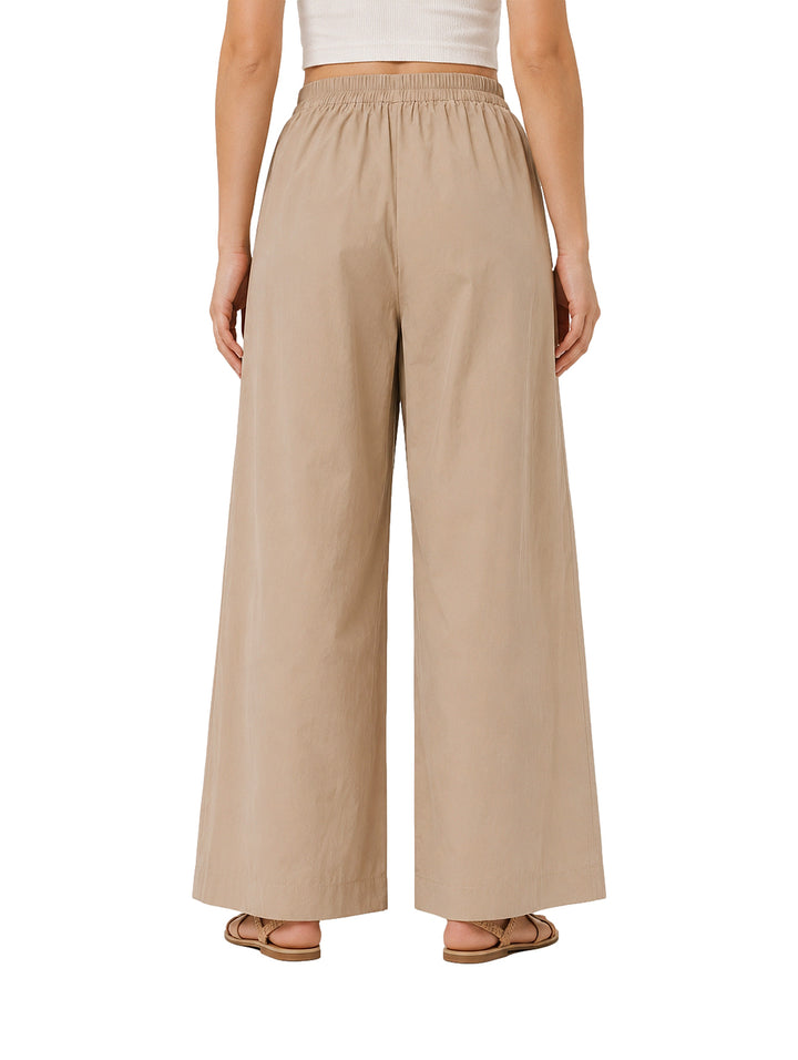 Mujer vistiendo pantalones de pierna ancha en color camel con cintura elástica.