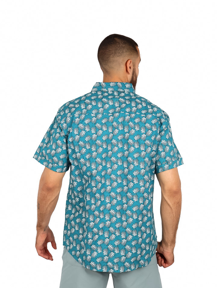 Hombre vistiendo una camisa casual de manga corta color azul claro con estampado de hojas blancas.