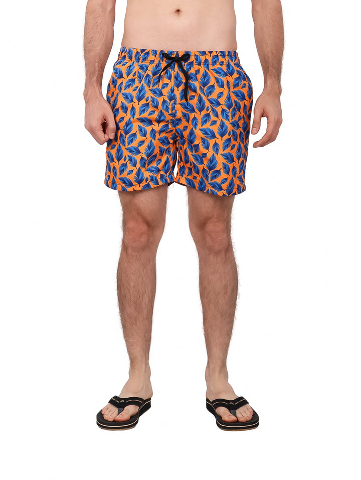 Traje de baño corto para hombre con estampado de hojas azules sobre fondo naranja.