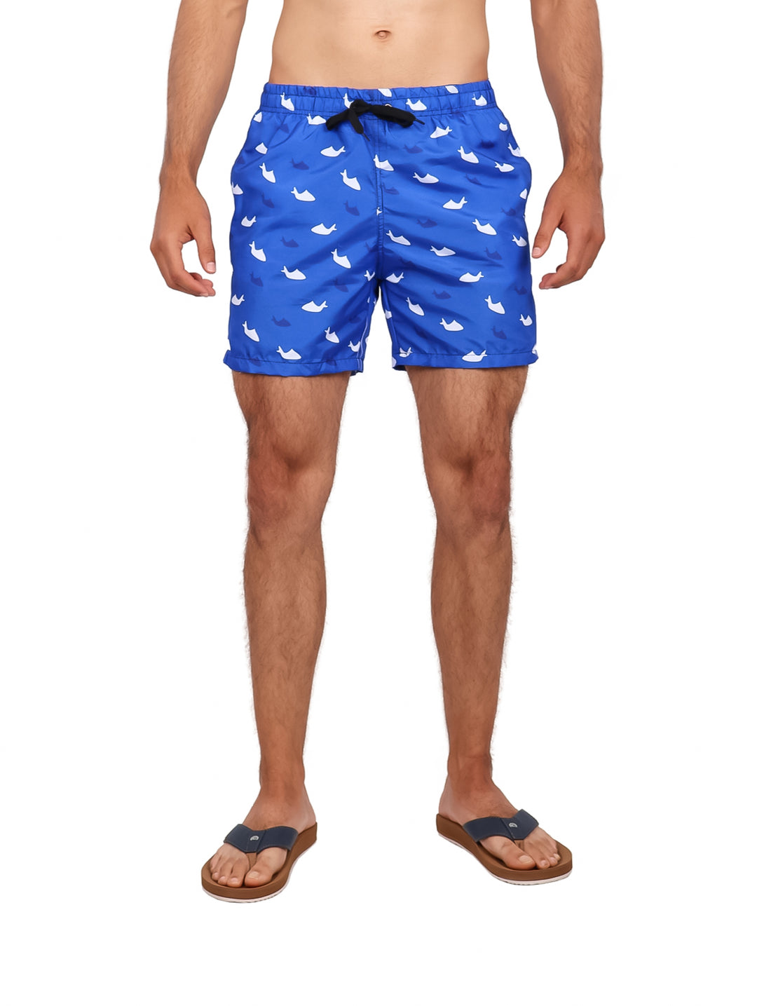 Hombre vistiendo traje de baño corto color azul royal con estampado de tiburones blancos.