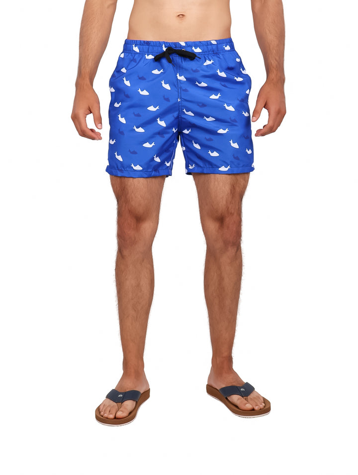 Hombre vistiendo traje de baño corto color azul royal con estampado de tiburones blancos.