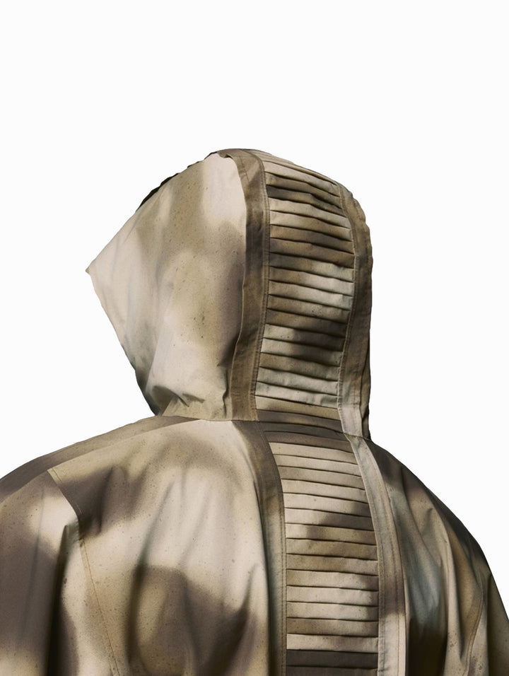 Dos personas vistiendo un poncho Columbia con estampado de camuflaje en tonos beige y marrón con capucha.