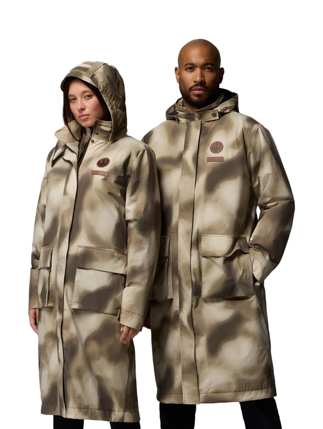 Hombre y mujer vistiendo gabardinas largas Columbia con estampado de camuflaje Buffalo Camo en tonos beige y café.