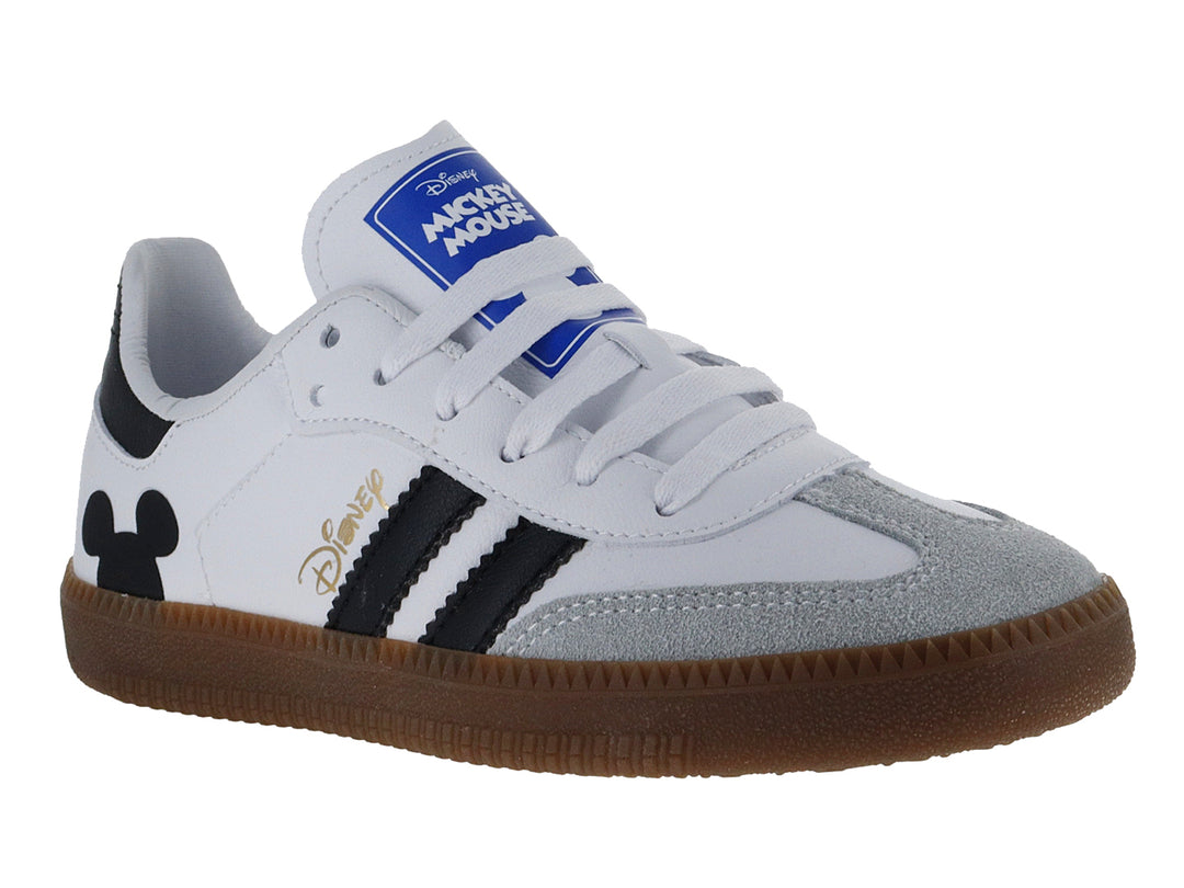 Tenis deportivos blancos con detalles en negro, suela marrón y diseño de Mickey Mouse.