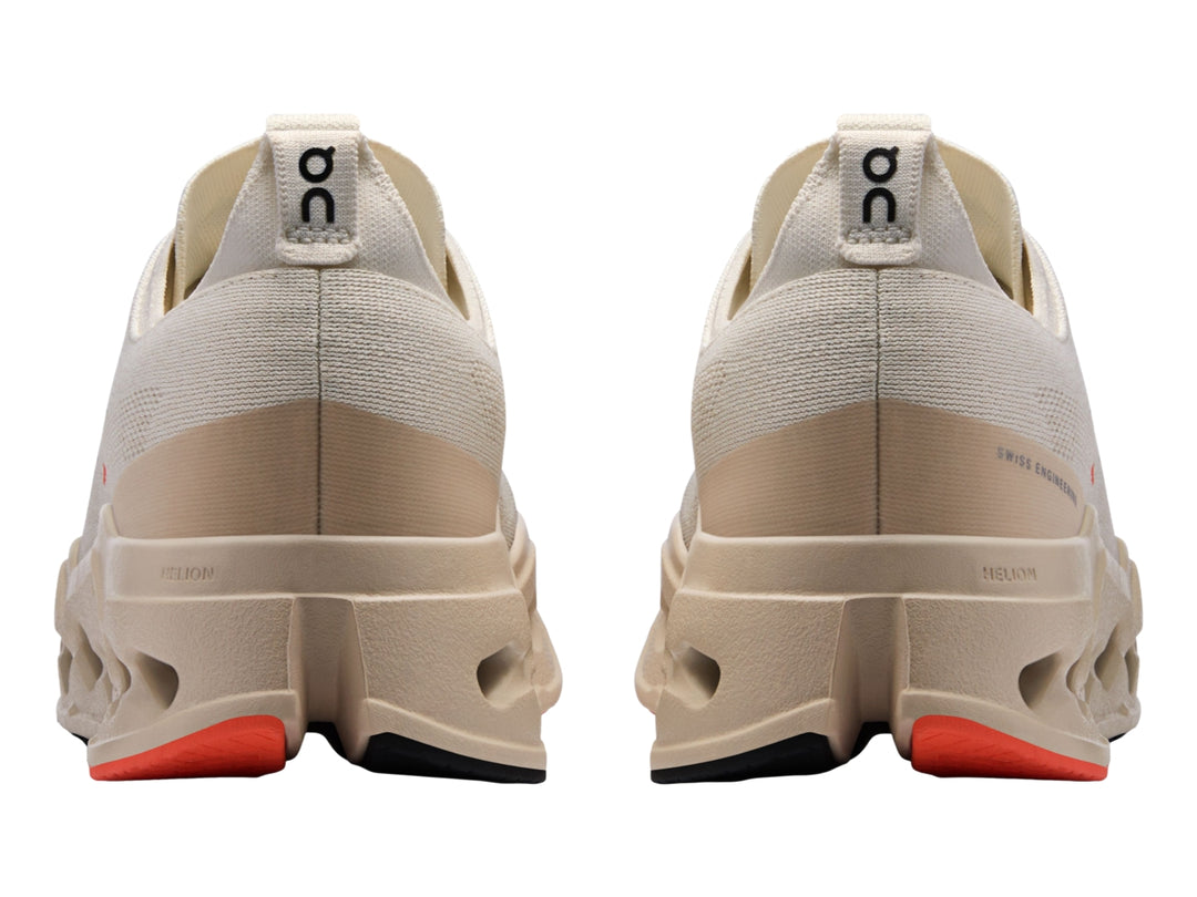 Tenis deportivos On Cloudsurfer Max color ivory con detalles en salmon y suela amortiguada.