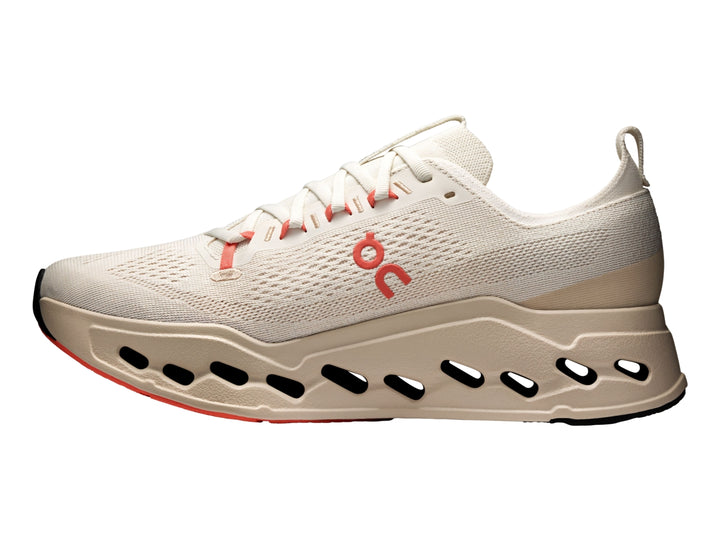 Tenis deportivos On Cloudsurfer Max color ivory con detalles en salmon y suela amortiguada.