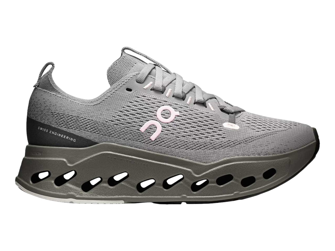 Tenis deportivos On Cloud color gris con suela gruesa perforada y logotipo rosa.