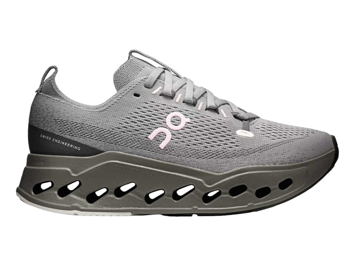 Tenis deportivos On Cloud color gris con suela gruesa perforada y logotipo rosa.
