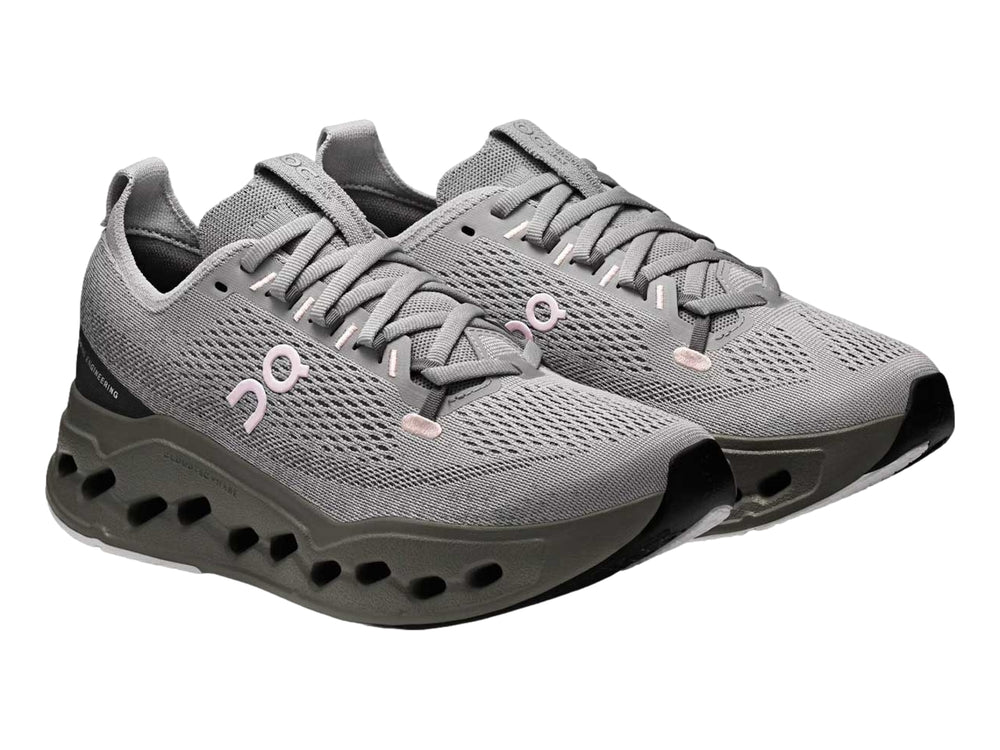 Tenis deportivos On Cloud color gris con suela gruesa perforada y logotipo rosa.