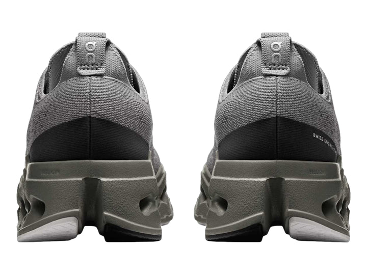Tenis deportivos On Cloud color gris con suela gruesa perforada y logotipo rosa.
