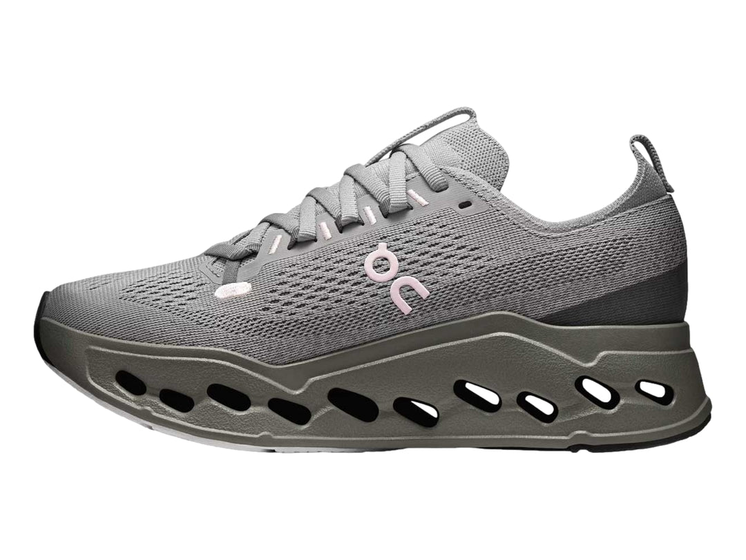 Tenis deportivos On Cloud color gris con suela gruesa perforada y logotipo rosa.