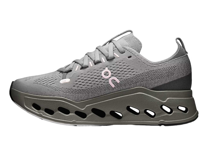 Tenis deportivos On Cloud color gris con suela gruesa perforada y logotipo rosa.