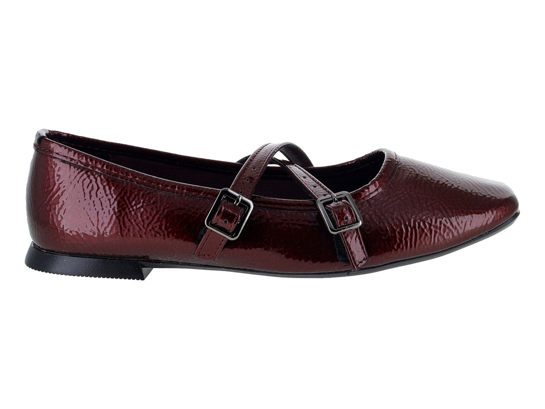 Zapato plano tipo ballerina color vino de charol arrugado con hebillas decorativas.
