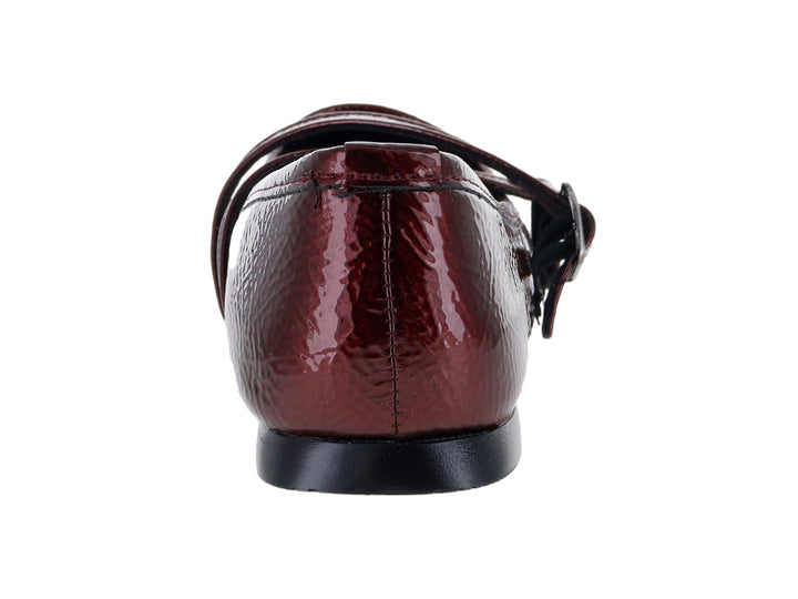 Zapato plano tipo ballerina color vino de charol arrugado con hebillas decorativas.