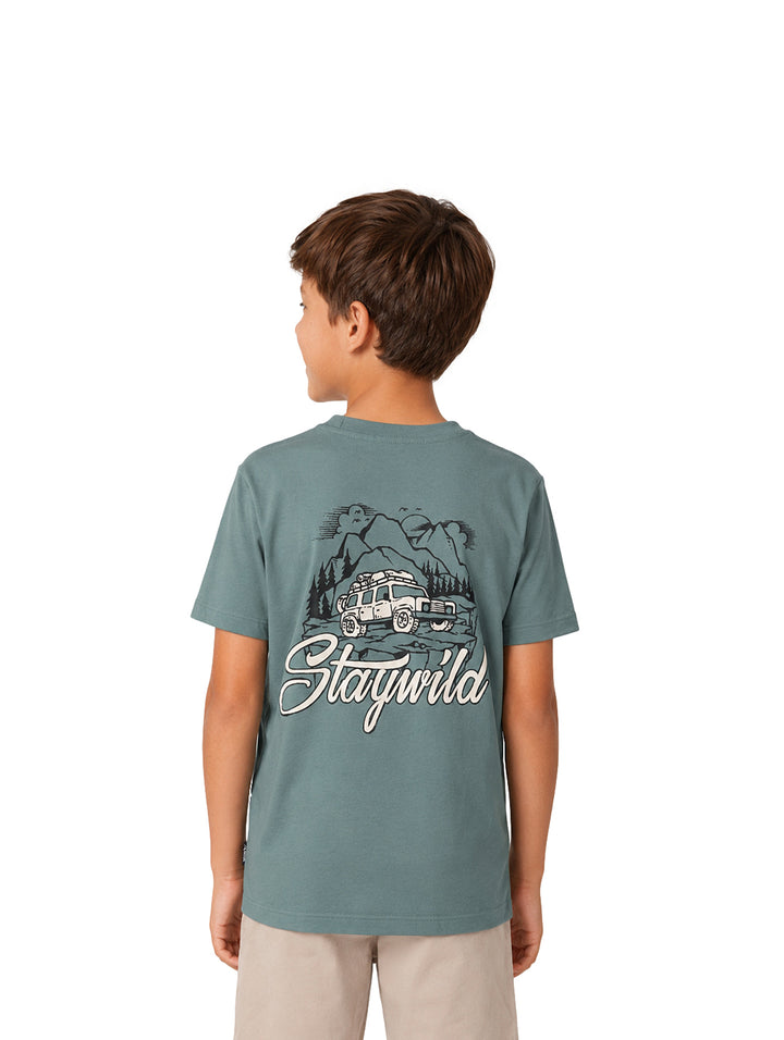 Niño vistiendo una camiseta de color verde sage con un estampado pequeño en el pecho.