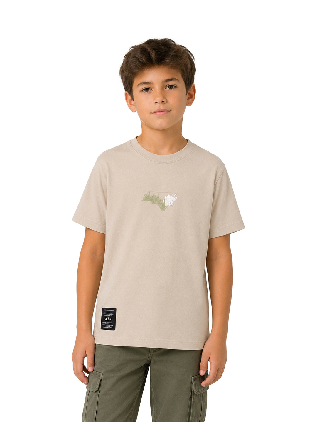 Niño vistiendo camiseta color sand con estampado central y etiqueta negra en la parte inferior.