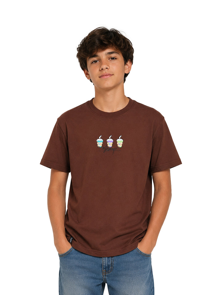 Niño vistiendo una camiseta color café con estampado frontal y pantalones azules.
