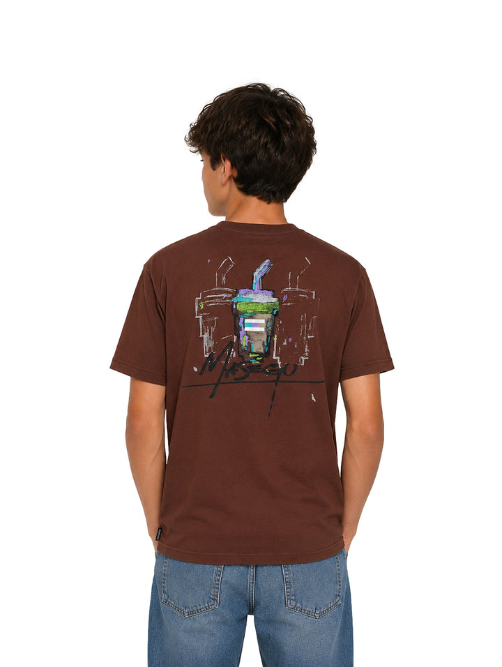 Niño vistiendo una camiseta color café con estampado frontal y pantalones azules.