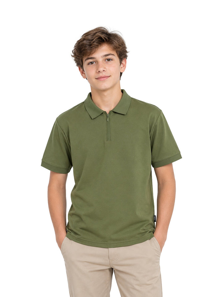 Niño vistiendo playera polo color verde militar con cierre en el cuello y pantalones beige.