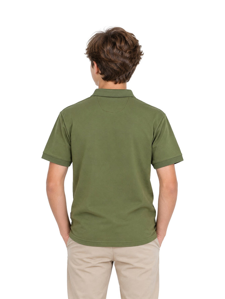 Niño vistiendo playera polo color verde militar con cierre en el cuello y pantalones beige.