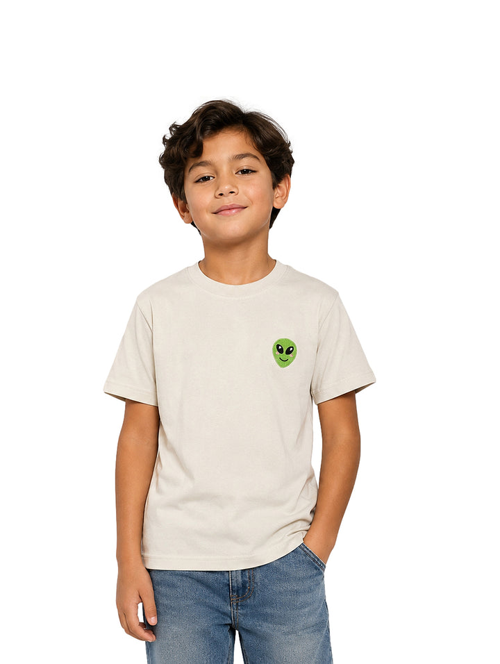 Niño vistiendo camiseta color ivory con un pequeño estampado de alienígena verde en el pecho.