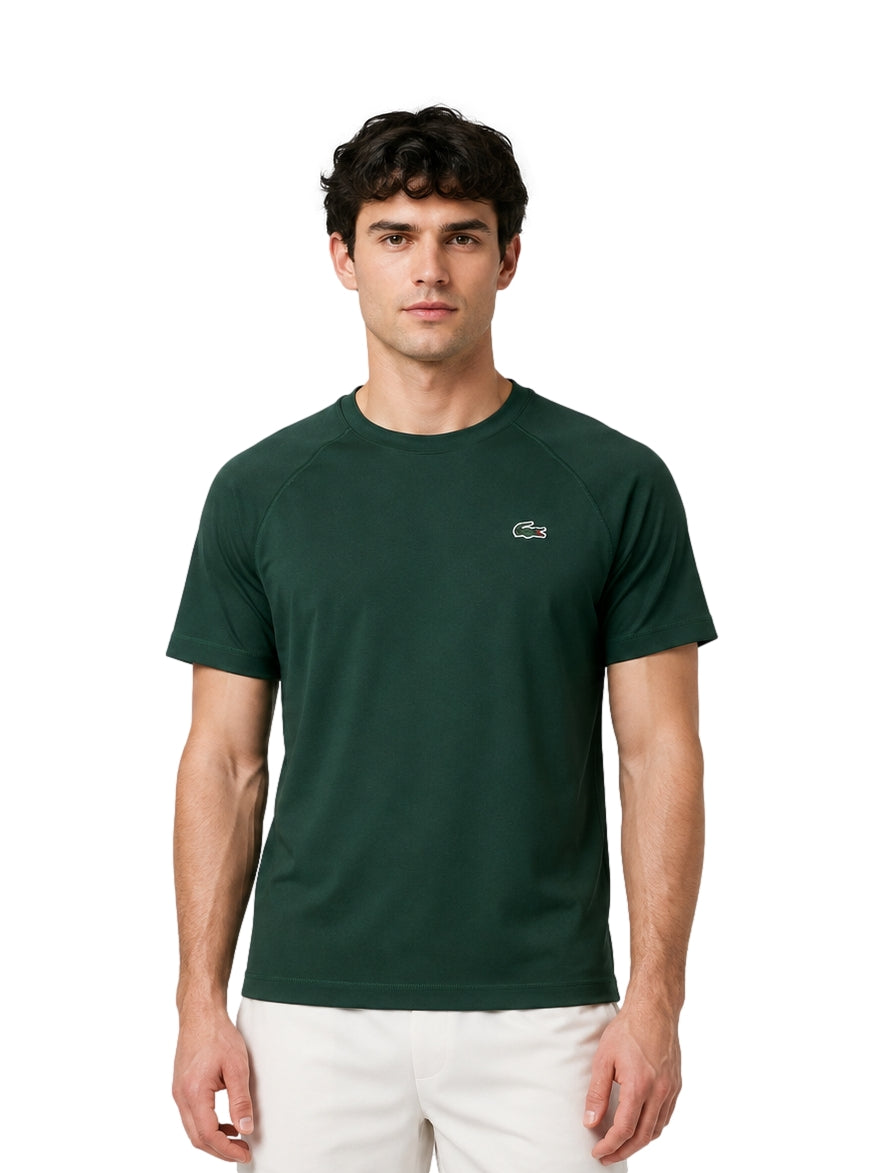 Hombre vistiendo una playera Lacoste de color verde oscuro con cuello redondo y manga corta.