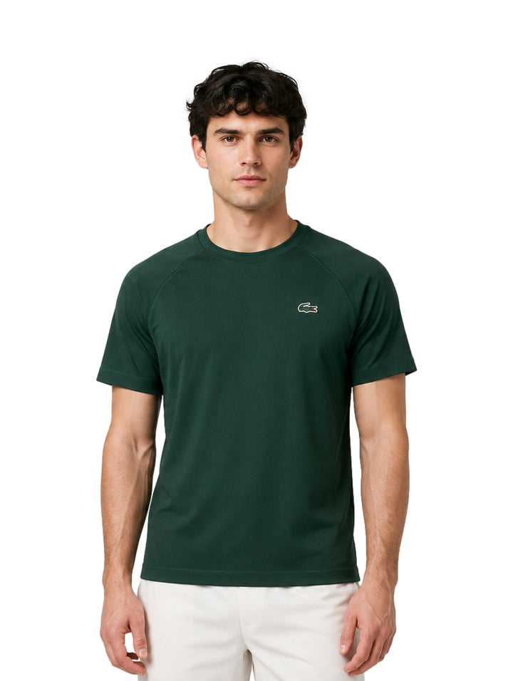 Hombre vistiendo una playera Lacoste de color verde oscuro con cuello redondo y manga corta.