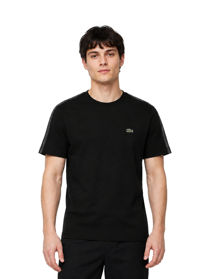 Hombre vistiendo playera Lacoste color negro de manga corta y cuello redondo.