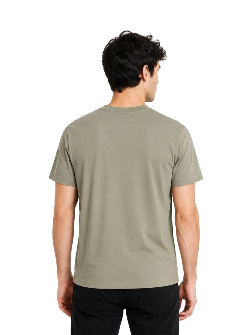 Hombre vistiendo playera Lacoste color khaki con detalles grises en los hombros y cuello redondo.