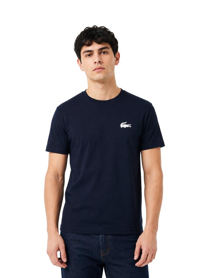 Hombre vistiendo playera Lacoste color navy de manga corta y cuello redondo.