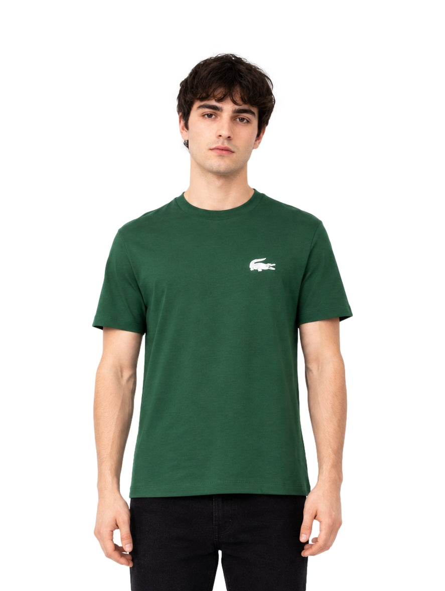 Hombre vistiendo una playera Lacoste de color verde con manga corta y cuello redondo.